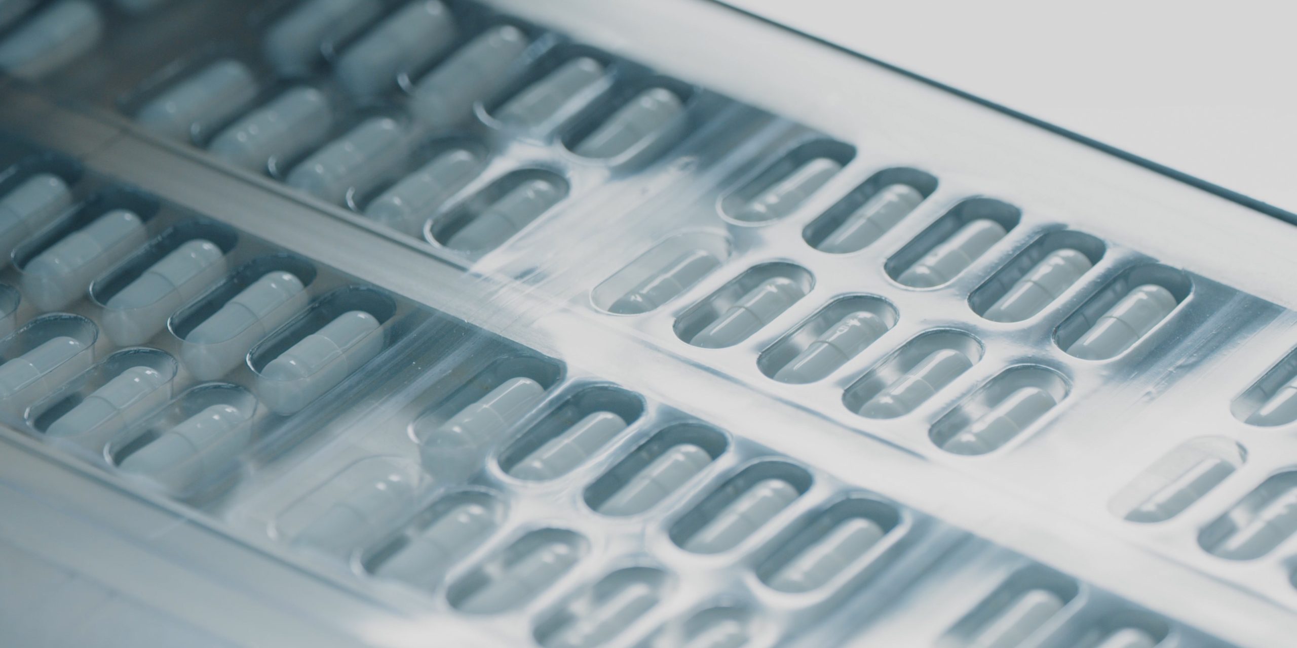 Blister packs with medicinal capsules move along the conveyor. Stage of fabrication. Plastic package with capsule meds. Medication capsules in blisters. Pharmaceutical factory production line